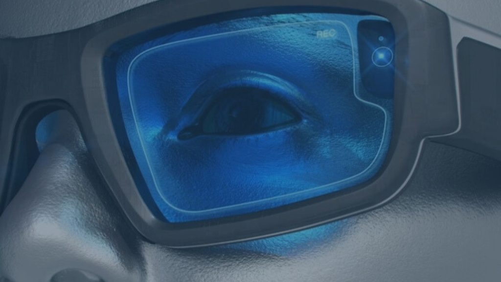 Close-up of an eye viewed through futuristic smart glasses lens showing a blue digital display and integrated camera sensor, to demonstrate an event vision.