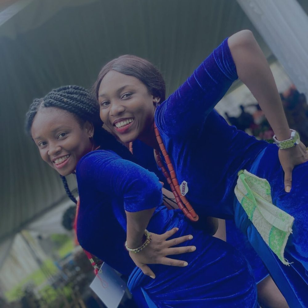 Mastering Body Language - Two smiling ushers in matching royal blue velvet outfits playfully pose together, one wearing red beads and an 'USHER' badge.